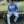 Load image into Gallery viewer, Person wearing a blue 'WISCO' sweatshirt sitting on a piece of farm equipment in a grassy field.
