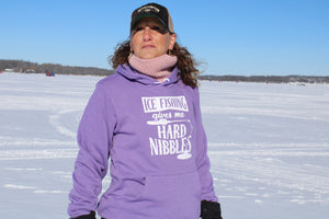 "Ice Fishing Gives Me the Hard Nibbles" hoodie, perfect for staying warm and showing humor during ice fishing trips. On female model who is ice fishing.