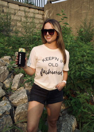 Woman wearing a 'Keepin' it Old Fashioned' t-shirt outdoors.