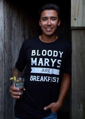 Man wearing a black t-shirt with 'Bloody Marys are Breakfast' text, holding a drink.