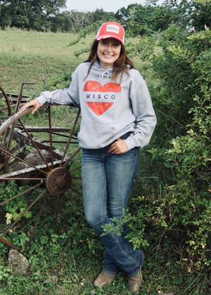 Person wearing a hoodie with 'Wisco' design in a rural setting