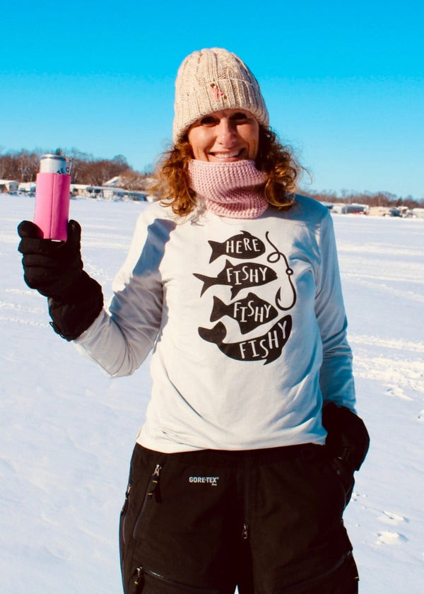 "Here Fishy Fishy Fishy" long sleeve t-shirt for fishing enthusiasts, perfect for outdoor adventures. On a female model who is ice fishing. 