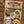 Load image into Gallery viewer, Wisconsin 'Northwoods' Pack sticker set in a clear plastic bag with a kraft paper header card reading 'WISCONSIN UP Authentic Wisco Wear,' shown on a wood plank background. The pack includes multiple camp-and-outdoor-themed stickers such as 'Rooted Here,' 'Stay Awhile,' 'Weekend Escape Wisconsin Up,' a jar sticker, and a circular 'Wisconsin UP' logo.
