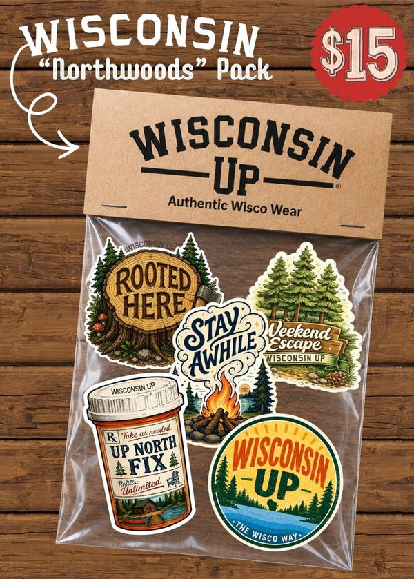 Wisconsin 'Northwoods' Pack sticker set in a clear plastic bag with a kraft paper header card reading 'WISCONSIN UP Authentic Wisco Wear,' shown on a wood plank background. The pack includes multiple camp-and-outdoor-themed stickers such as 'Rooted Here,' 'Stay Awhile,' 'Weekend Escape Wisconsin Up,' a jar sticker, and a circular 'Wisconsin UP' logo.