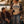 Load image into Gallery viewer, Four friends gathered around a campfire at dusk by a lake, wearing flannel shirts and beanies. The standing woman wears a cream graphic T-shirt that reads 'WISCONSIN UP OUTFITTERS' with a blue mountain-and-river logo.
