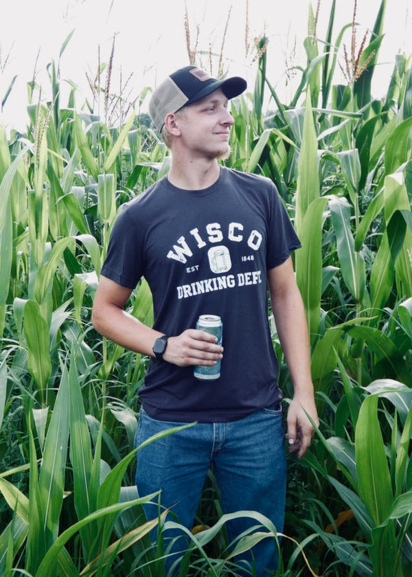 Man standing in a cornfield wearing a navy t-shirt with 'Wisco Drinking Dept' text.