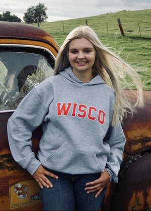 Person wearing a 'WISCO' hoodie standing next to an old truck in a rural setting