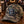 Load image into Gallery viewer, A camouflage trucker hat with a blue and white 'WI UP' patch on the front, displayed on a wooden bar counter next to a Miller Lite bottle in a bar setting.
