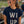 Load image into Gallery viewer, A young woman in a navy blue t-shirt with 'WI UP' printed on the front, sitting in an outdoor stadium at sunset. The shirt features a navy blue background with 'WI' in cream and 'UP' in navy, separated by a thin red line, with a navy paw print graphic on the 'I'.
