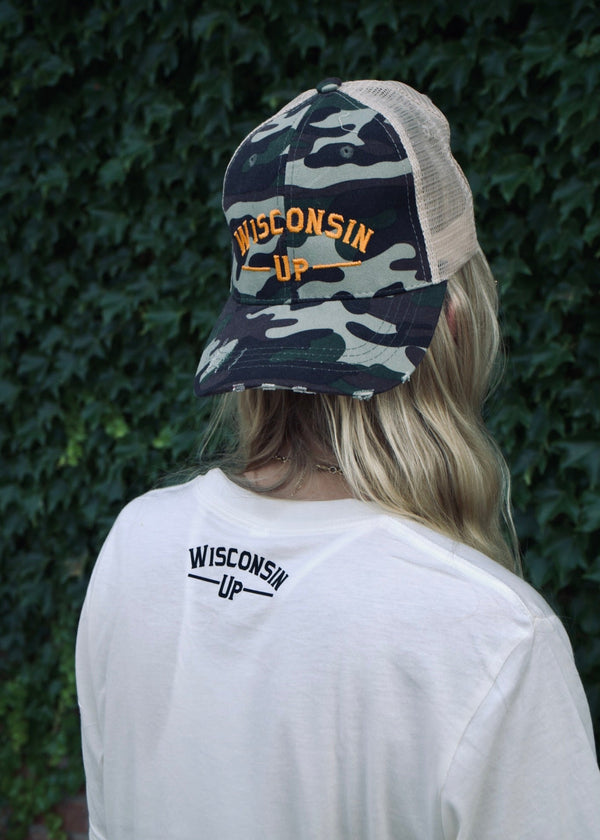 Person wearing a camouflage cap and white t-shirt with 'Wisconsin Up' text against a green leafy background