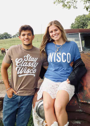 Two people wearing 'Stay Classy Wisco' and 'WISCO' shirts sitting on a truck bed outdoors.