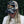 Load image into Gallery viewer, Person wearing a white t-shirt with a graphic design and a camouflage cap, standing against a dark green leafy background.
