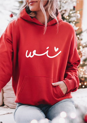 Person wearing a red hoodie with 'wi' text in front of a decorated Christmas tree.