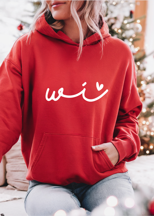 Person wearing a red hoodie with 'wi' text in front of a decorated Christmas tree.