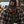 Load image into Gallery viewer, A man wearing a black and tan trucker hat with a leather patch logo sits outdoors by a lake, holding a can cooler.
