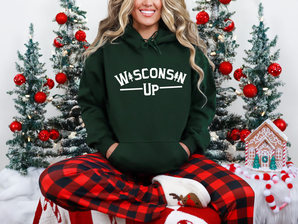 Person wearing a green 'Wisconsin Up' hoodie in front of Christmas trees.